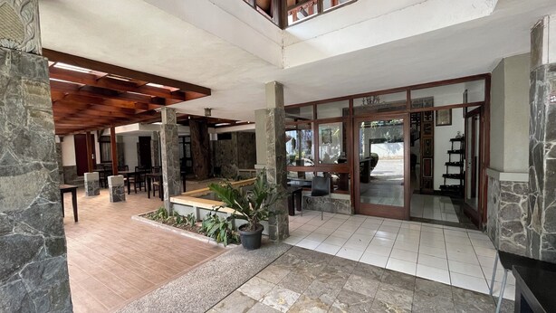 A spacious lobby with a high ceiling, stone pillars, and a mix of tiled and wooden flooring. - Hotel Gegerkalong Asri (Bandung)