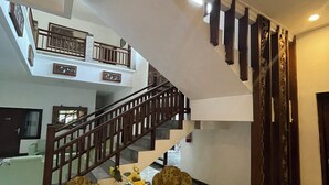 A spacious living area with a staircase leading to an upper floor, featuring a modern design with a wooden railing and a decorative wall panel. - Hotel Gegerkalong Asri (Bandung)
