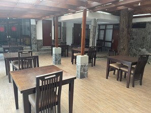 A restaurant with wooden tables and chairs, stone pillars, and a stone wall. - Hotel Gegerkalong Asri (Bandung)