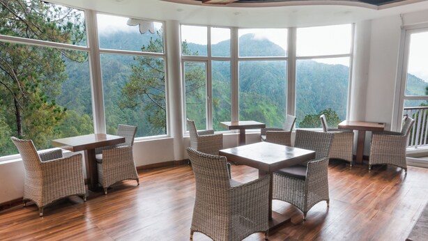 Quarto com janelas amplas, móveis de vime e piso de madeira.
