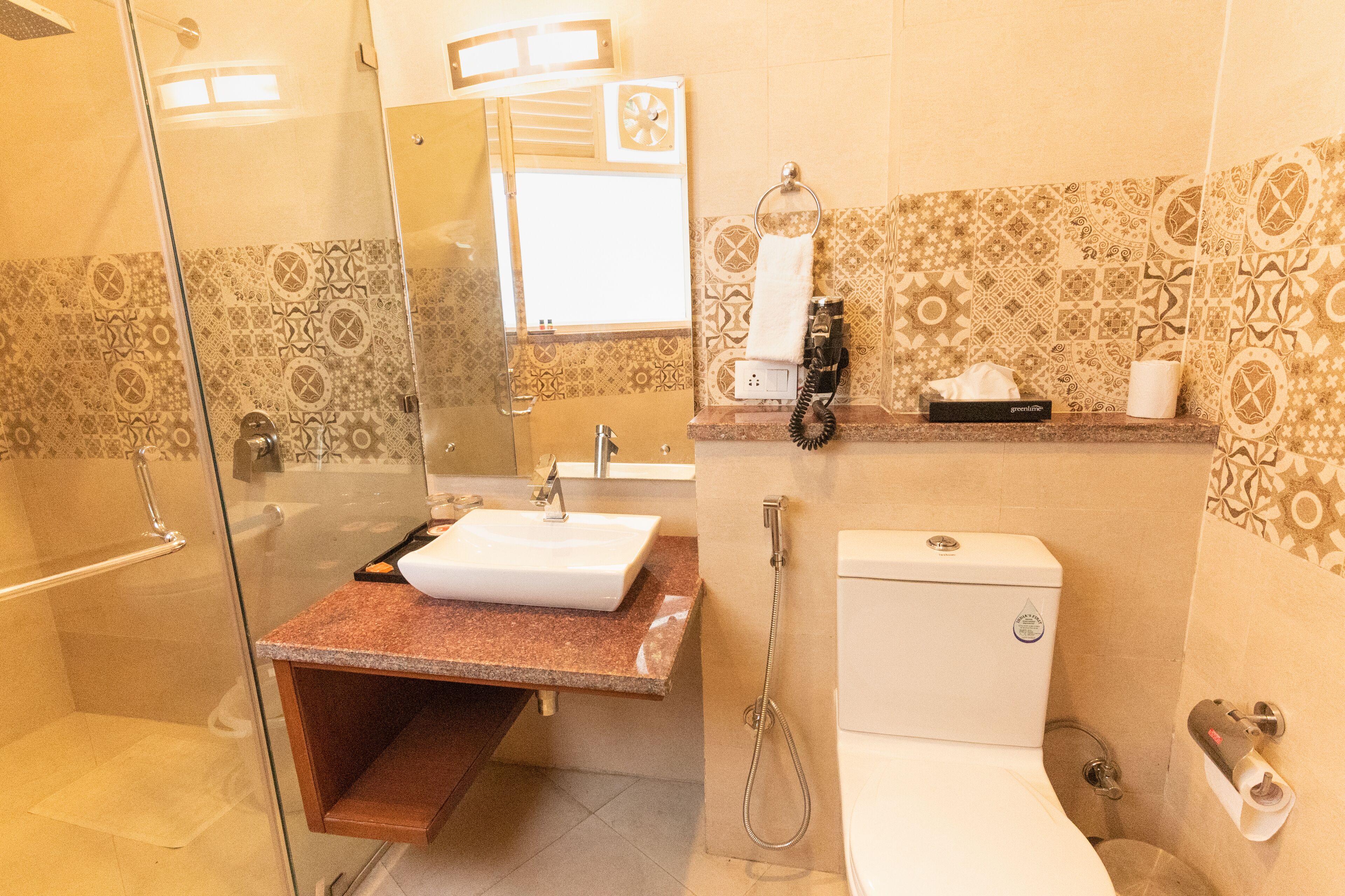 A bathroom with a glass-enclosed shower, a sink, and a toilet.