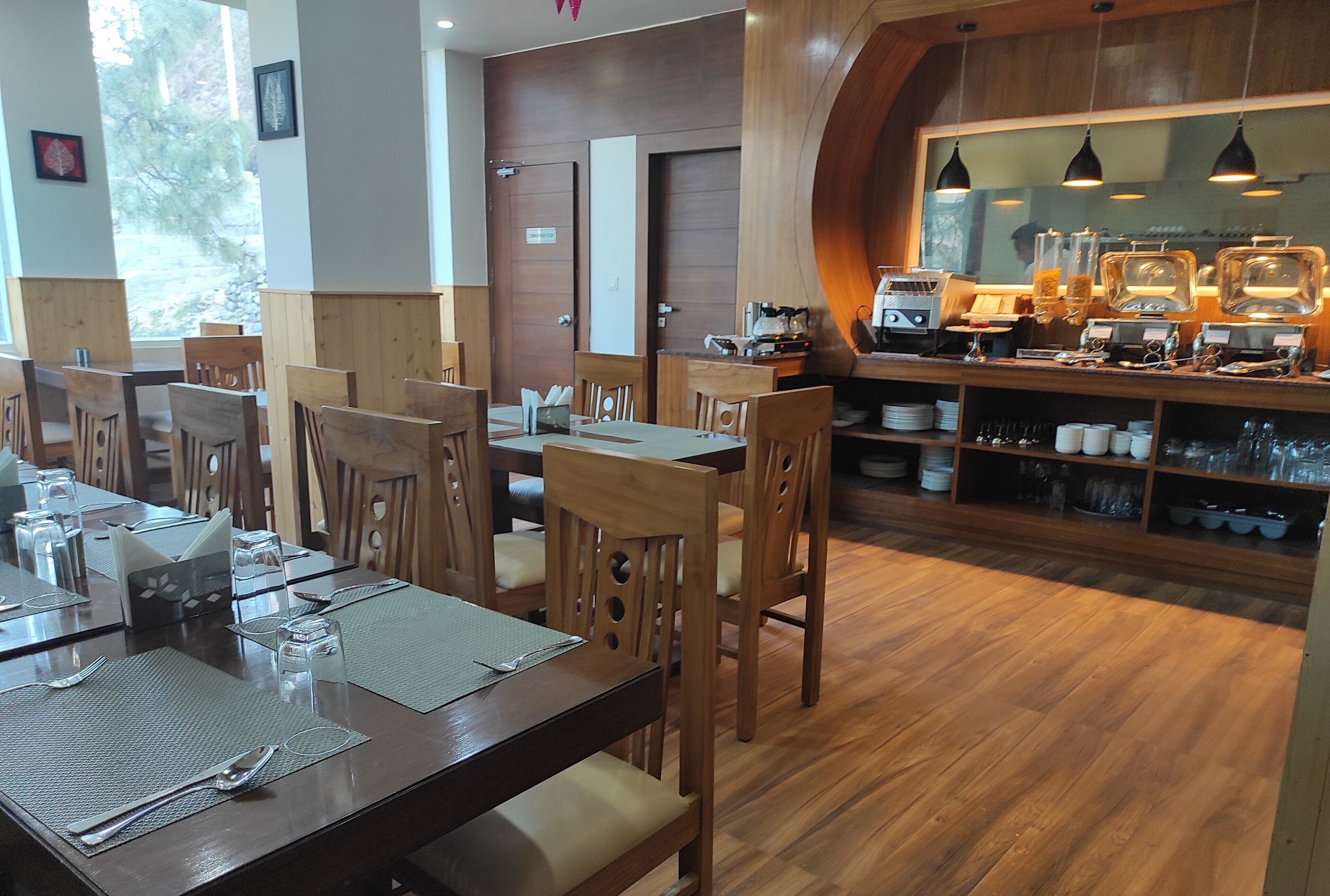 Un restaurante con mesas y sillas de madera, una barra de café y vistas al exterior.