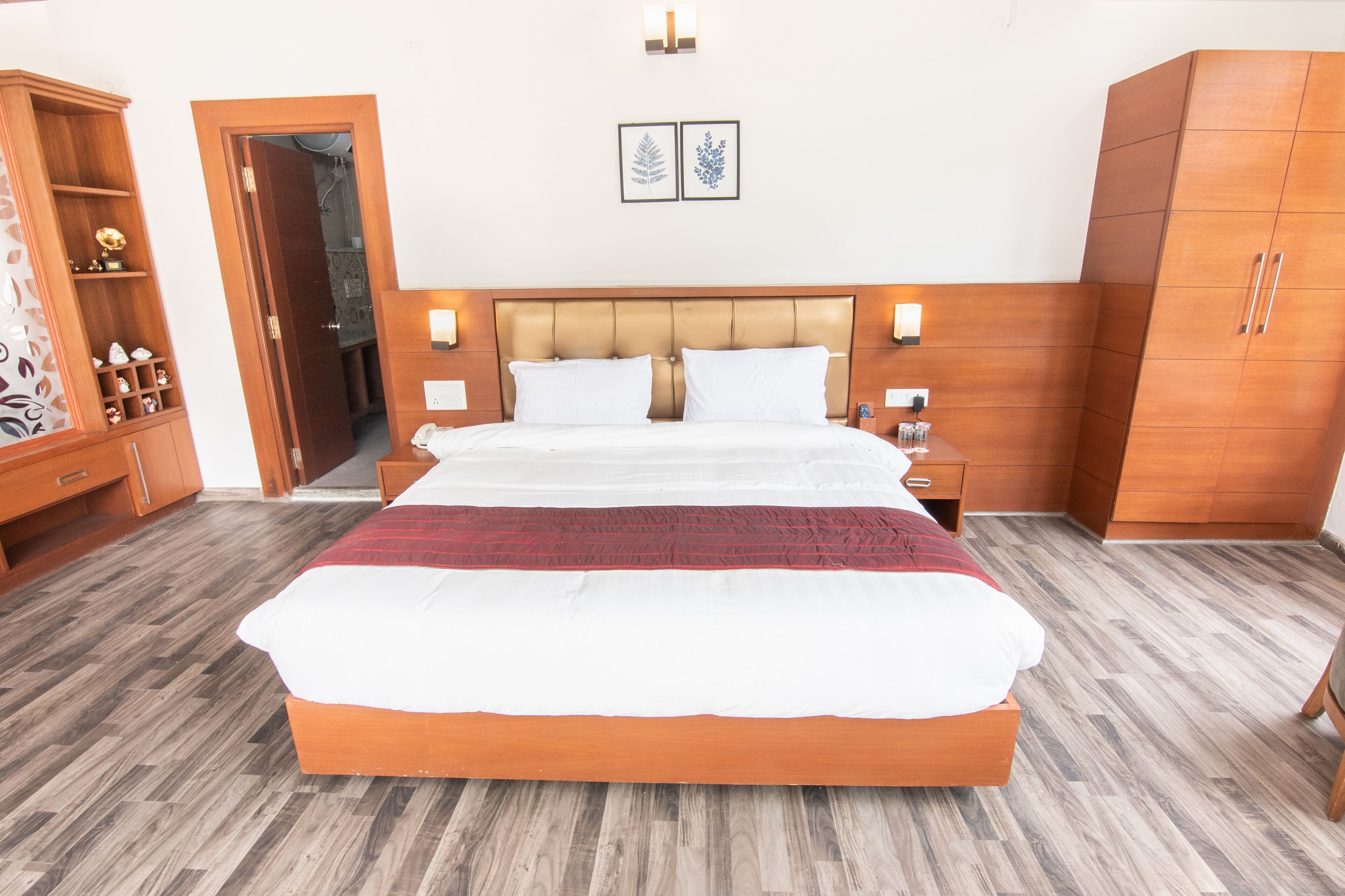 Une chambre à coucher avec un grand lit, une armoire en bois et une table de chevet avec une lampe.