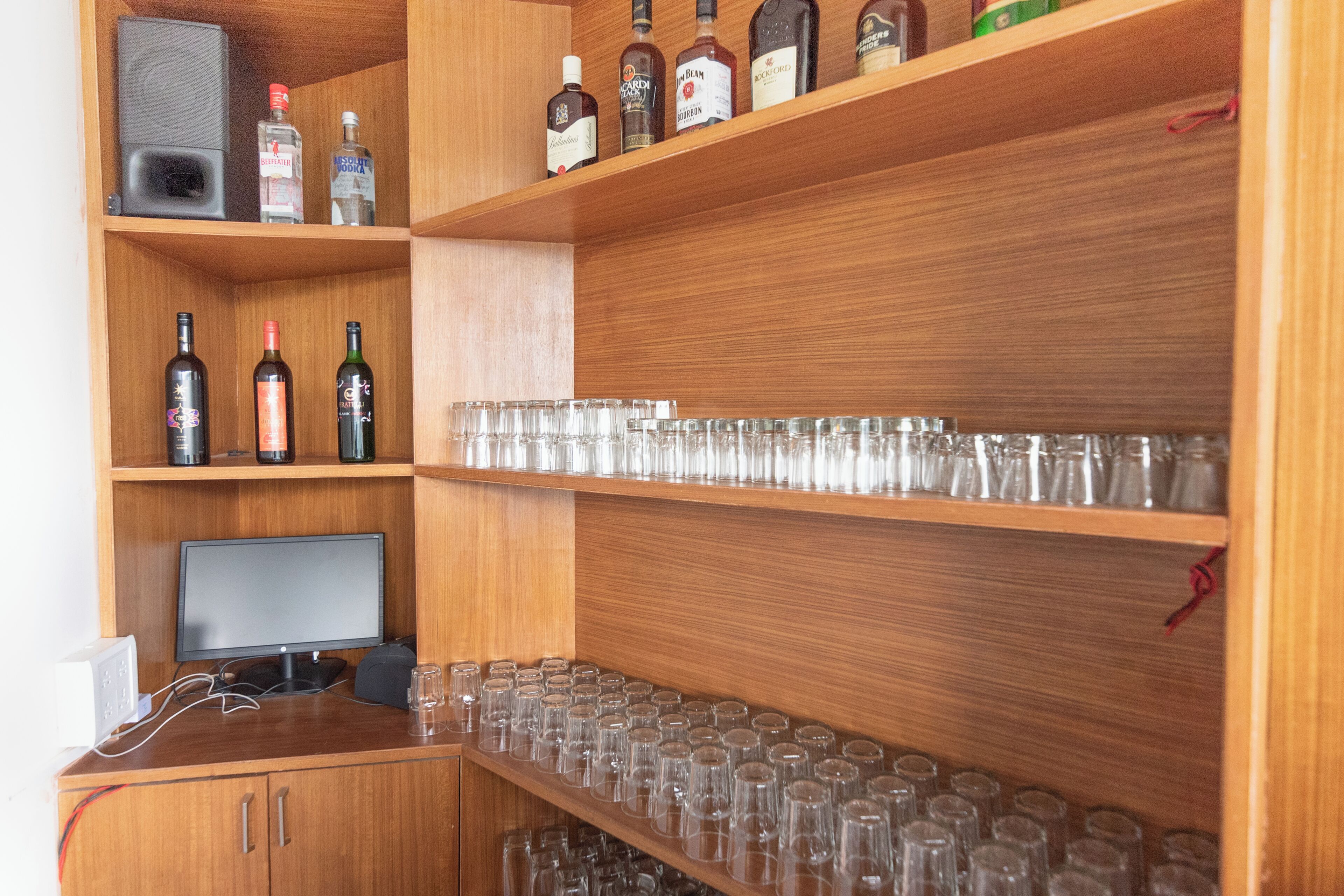 Un estante de madera con botellas de licor y vasos.