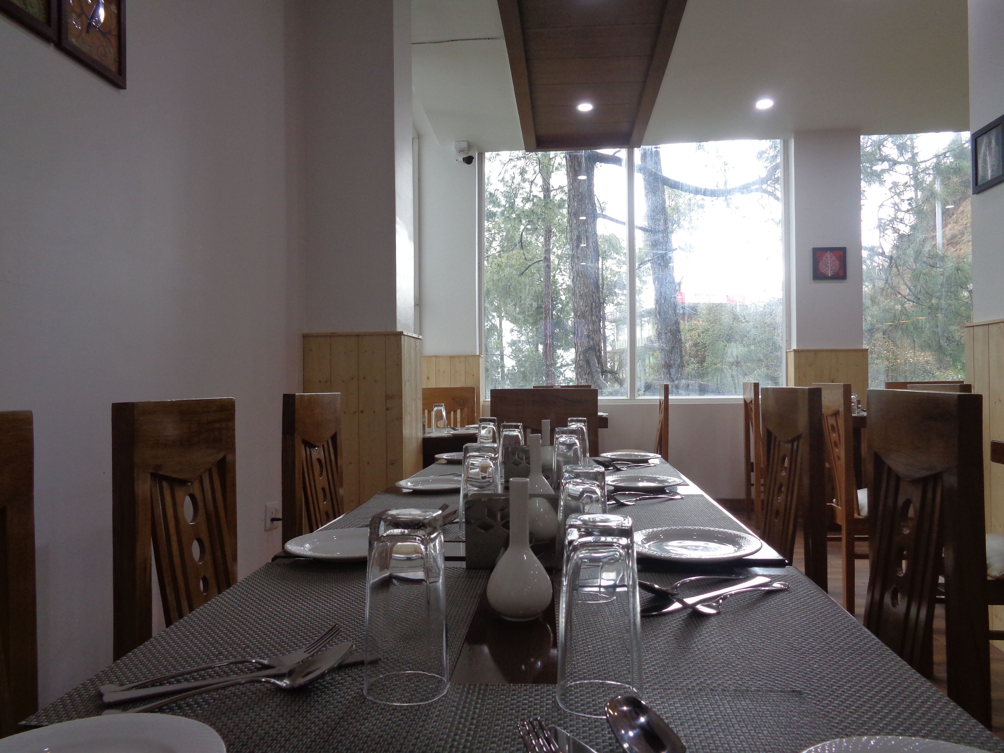 A dining table set with plates, cutlery, and glasses, with chairs around it.