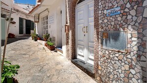 Una estrecha calle adoquinada con un edificio de piedra que presenta una puerta blanca y un letrero que dice 'CASA TULLIO'.