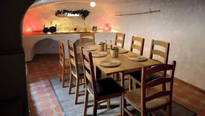 Un coin repas agrémenté d’un mur en pierre rustique, d’une table en bois et de chaises.