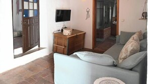 Un salon chaleureux avec un meuble en bois, un téléviseur et un canapé agrémenté de coussins à motifs.