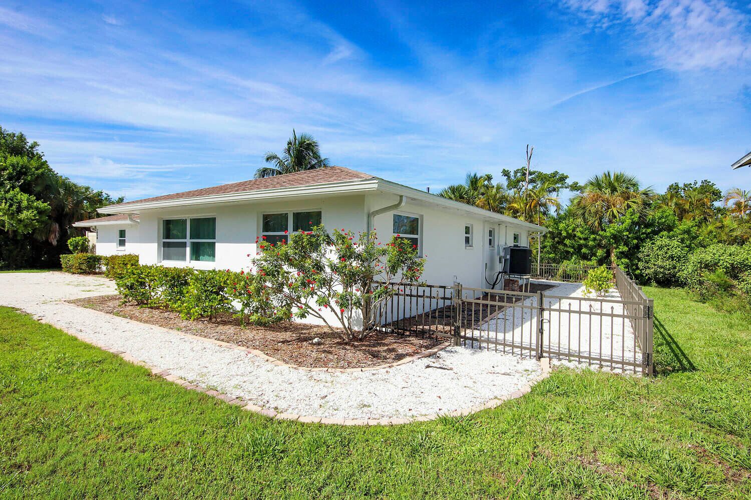 A single-story house with a white exterior, a covered porch, and a fenced yard.