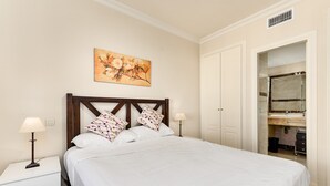 A neatly made bed with white bedding, a wooden headboard, and two bedside lamps. - Apartment 'Casa Vasari' with Sea View, Wi-Fi and Air Conditioning (Manilva)