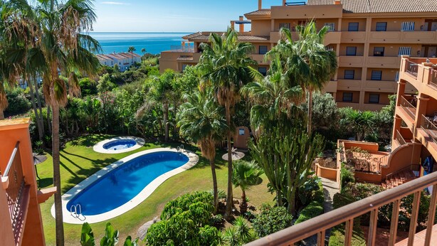 A hotel with a swimming pool, palm trees, and a view of the ocean. - Apartment 'Casa Vasari' with Sea View, Wi-Fi and Air Conditioning (Manilva)