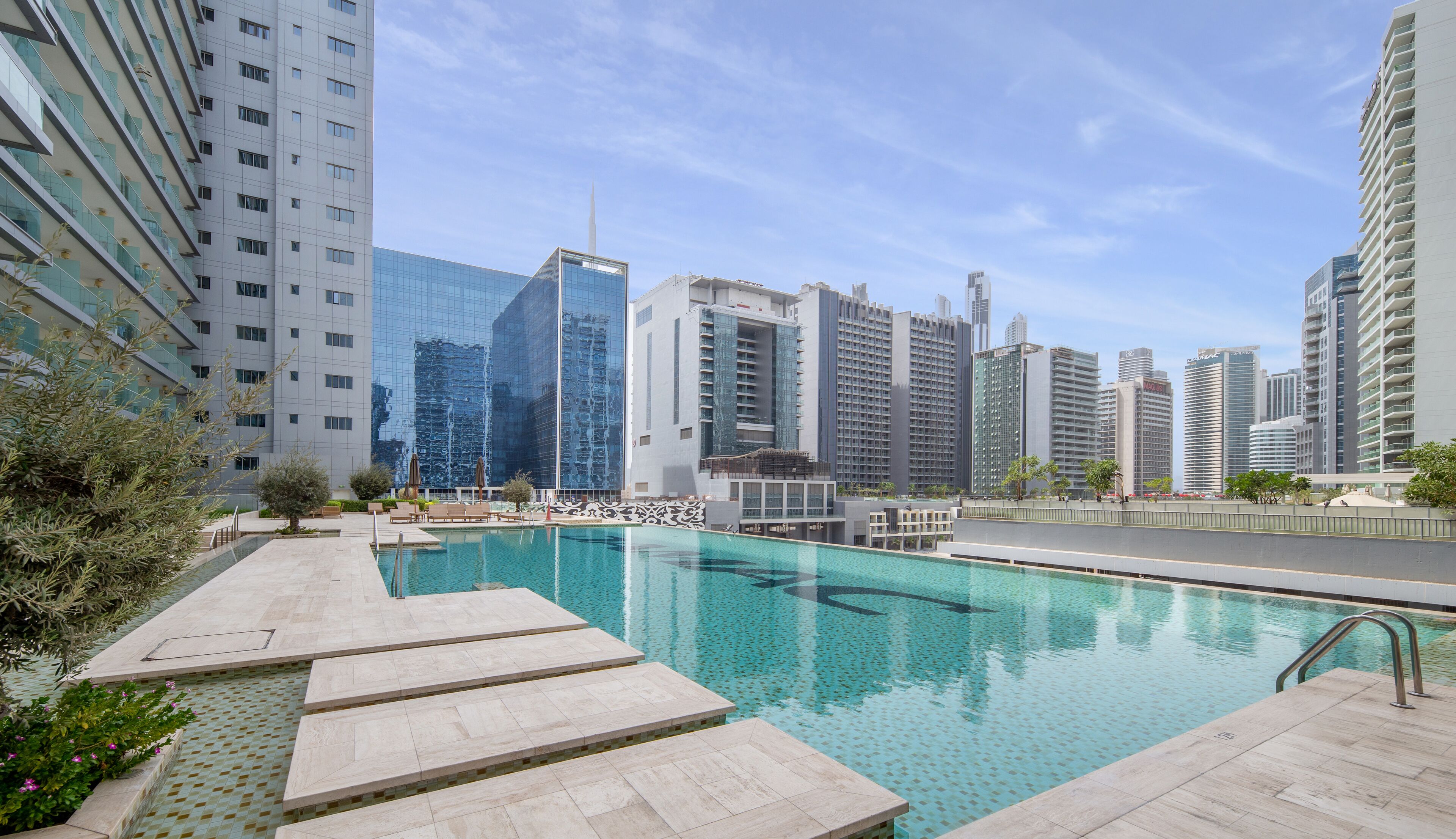 A modern hotel pool area with a clear view of surrounding high-rise buildings.