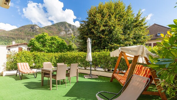 Un patio al aire libre con un columpio, mobiliario de mimbre y vistas a las montañas.