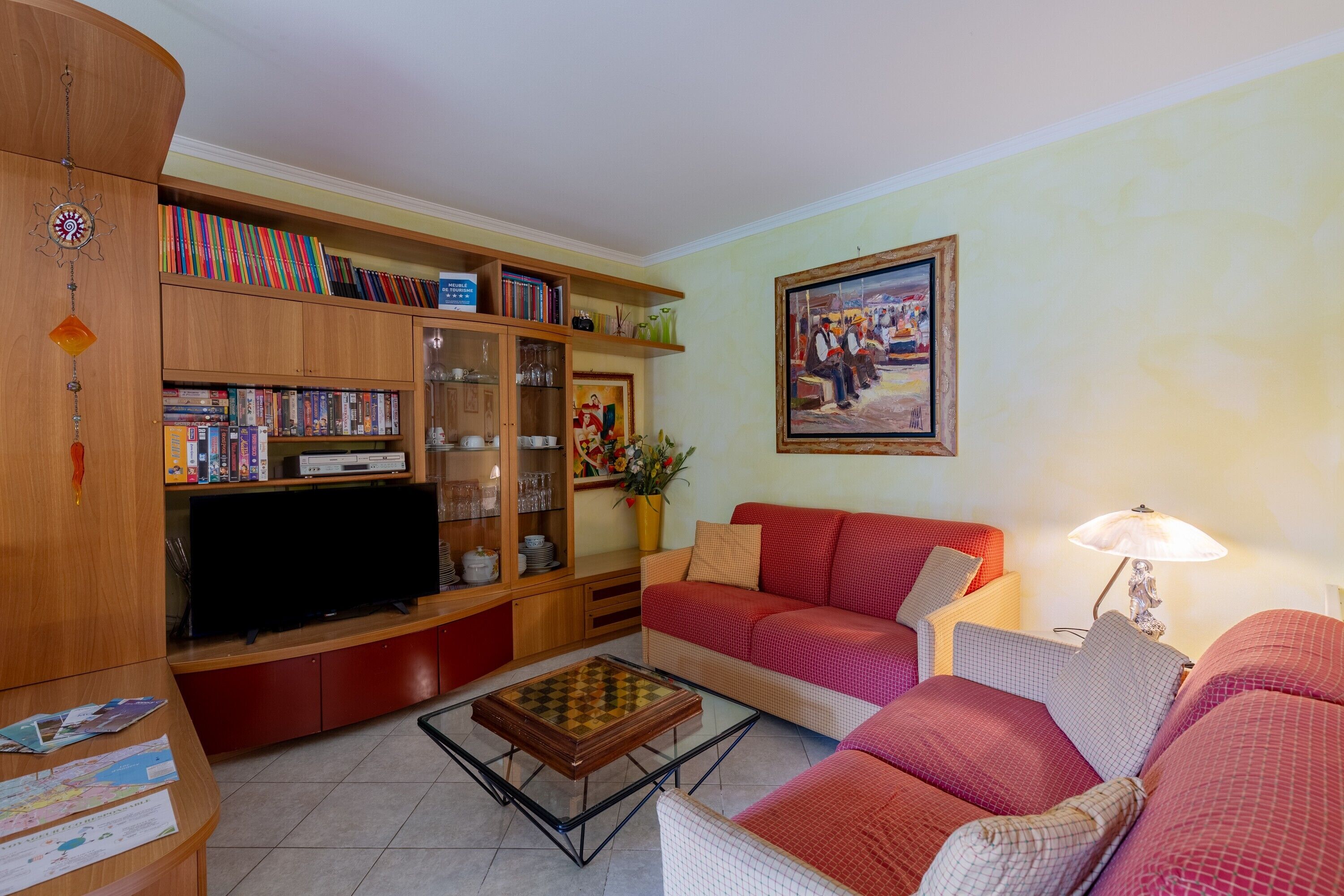 A living room with a sofa, television, bookshelves, and a painting.