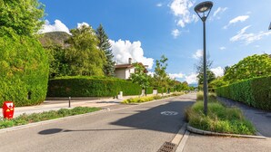Una calle residencial con una casa, una farola y una señal de límite de velocidad.