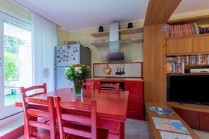 A kitchen with a dining table, chairs, a refrigerator, and a bookshelf. - Holiday Apartment 'Maison Bruno' with Private Terrace & Wi-Fi (annecy le vieux)