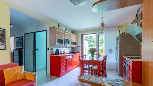 Una cocina moderna con armarios rojos, una zona de comedor con sillas de madera y un sofá rojo.