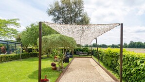 A garden with a wooden pergola, a sandbox, and various plants. - Large Family Villa with Private Heated Pool in Landes (Clermont)
