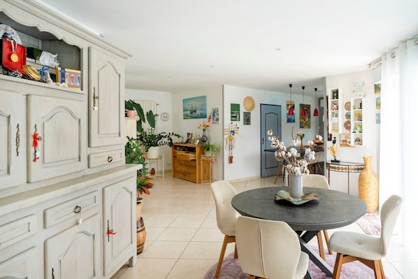 A spacious kitchen with a dining area, featuring a large cabinet, a round table with chairs, and various decorative items.