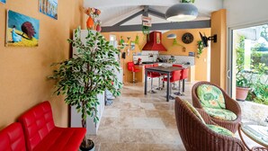 A modern kitchen with red chairs, a dining table, and a large potted plant. - Large Family Villa with Private Heated Pool in Landes (Clermont)
