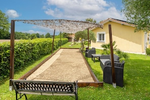 A garden area with a bench, outdoor furniture, and a pergola structure.