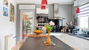 A modern kitchen with a central island, pendant lights, and a vase with flowers. - Large Family Villa with Private Heated Pool in Landes (Clermont)