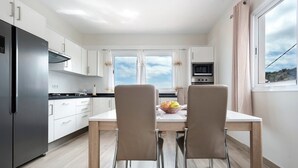 Una cocina moderna con refrigerador, horno y mesa de comedor con sillas.