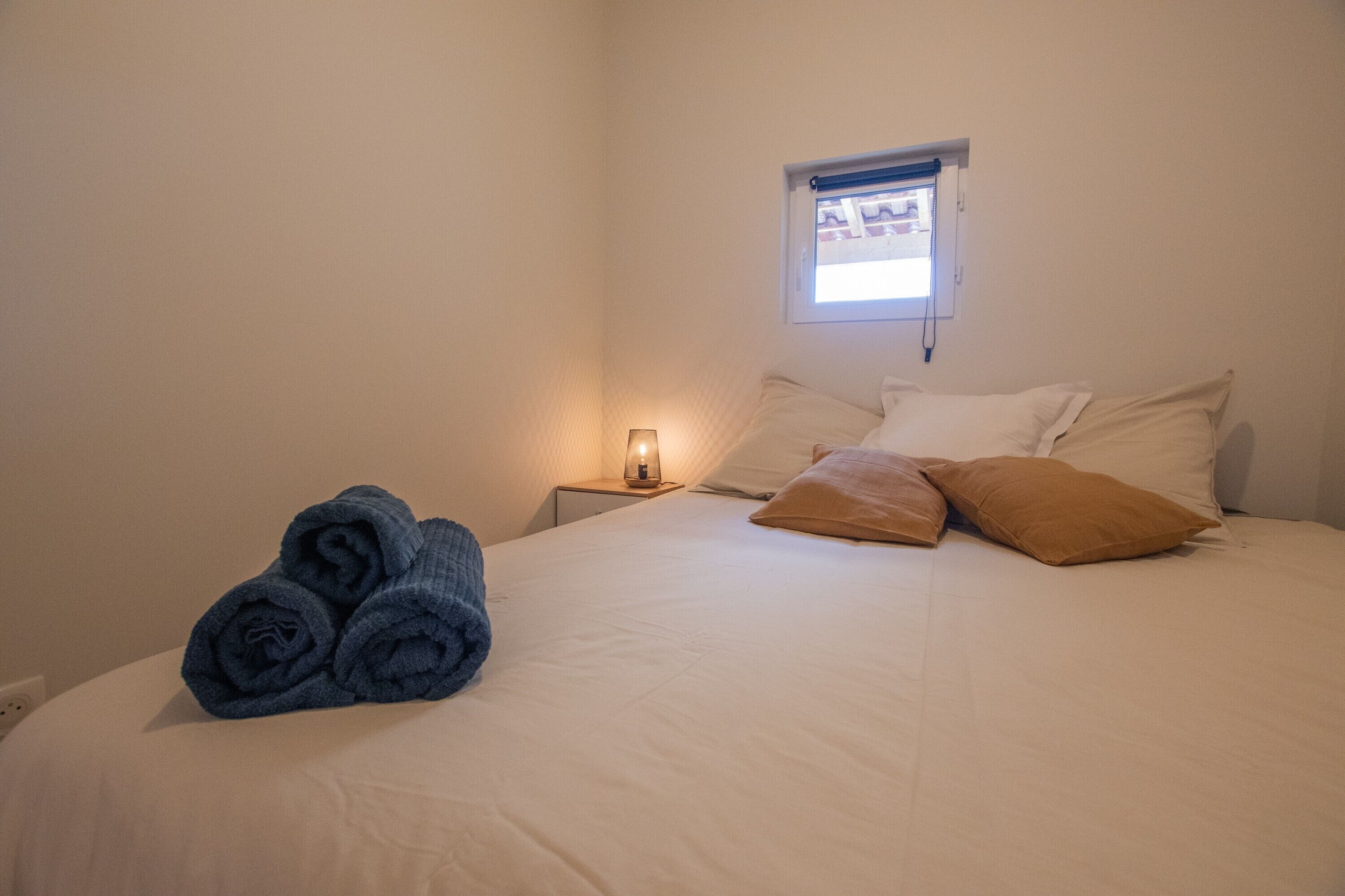 Una camera da letto con un letto, un comodino, una lampada e una finestra.