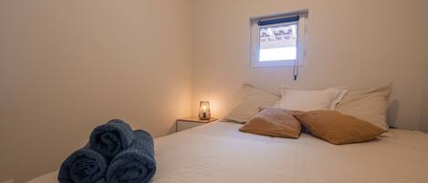 Una camera da letto con un letto, un comodino, una lampada e una finestra.