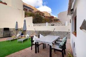 Un patio con tavolo e sedie, un barbecue e vista sulle montagne.
