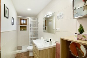 Un bagno con un WC, un lavandino, uno specchio e una doccia.