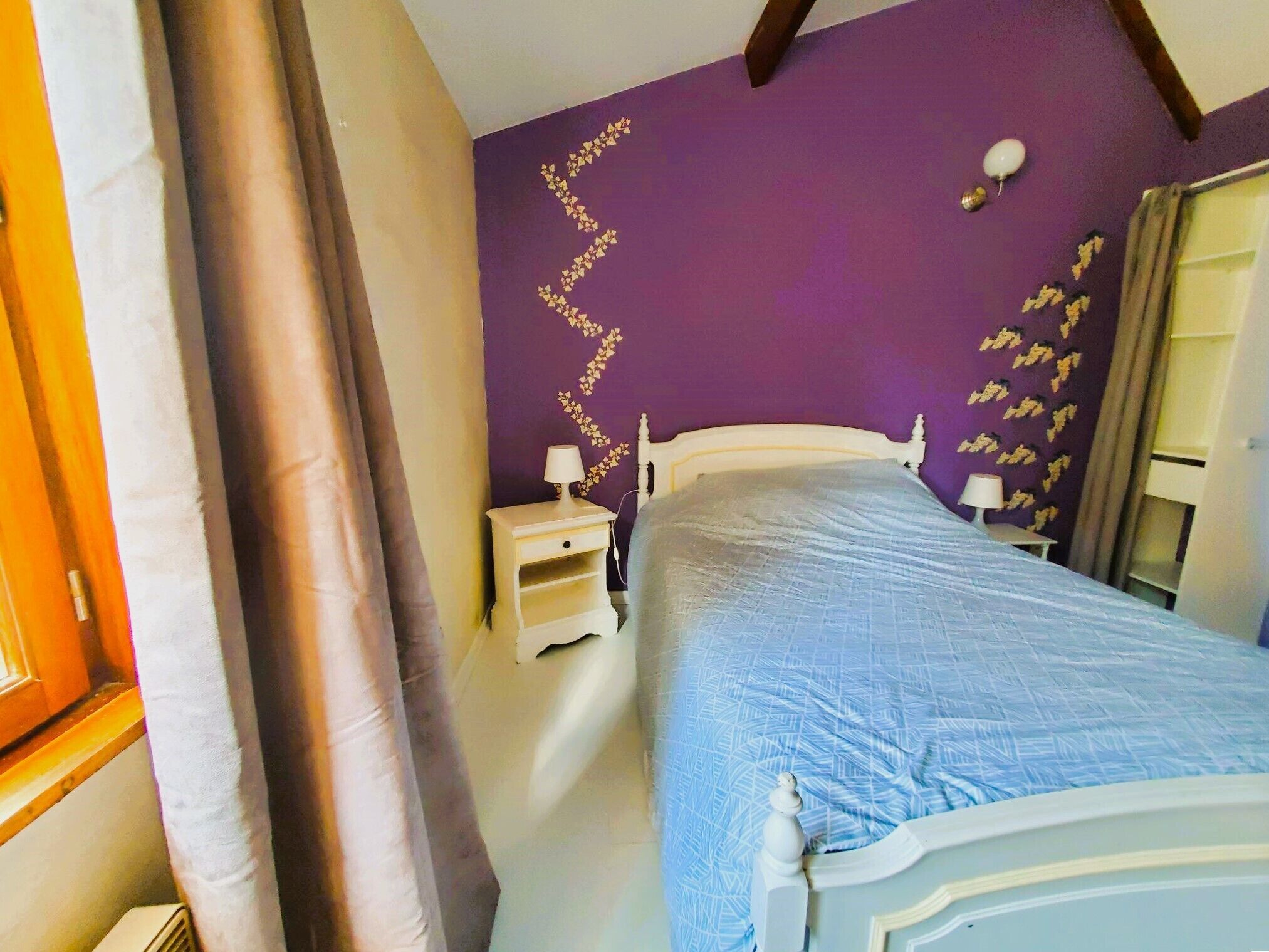 A bedroom with a bed, nightstand, and a wall with a decorative pattern.