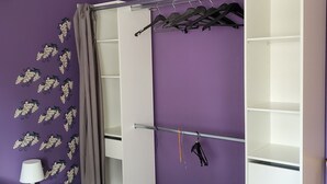 Ein Schlafzimmer mit Bett, Kleiderschrank, Spiegel, Lampe und einer Wand mit einem Weinrebenmuster.