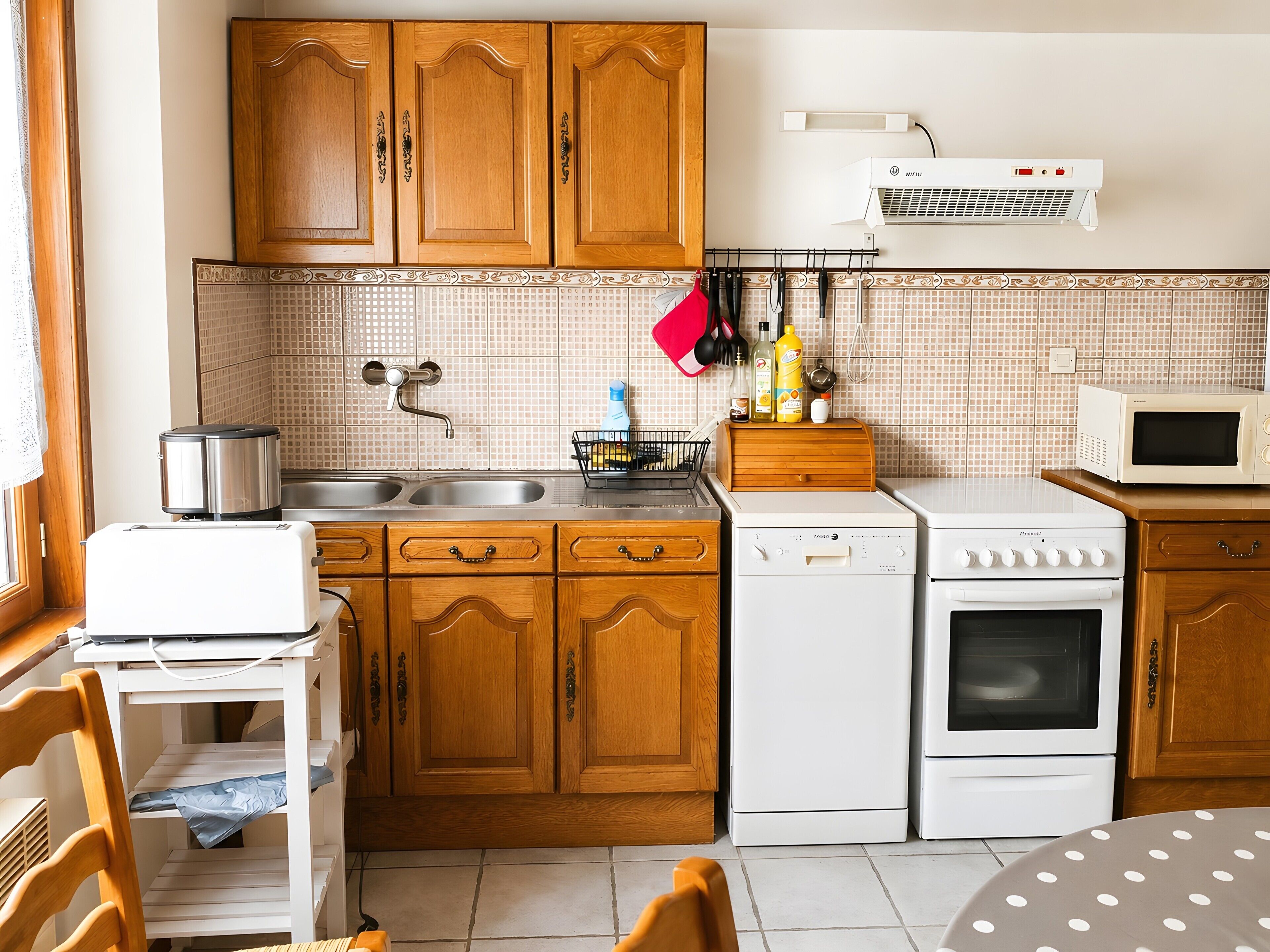 Cucina con mobili in legno, lavello, lavastoviglie, piano cottura e forno a microonde.