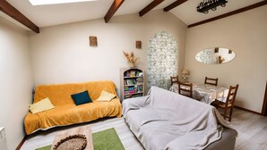 Ein gemütliches Wohnzimmer mit Sofa, Esstisch, Bücherregal und einem dekorativen Spiegel.