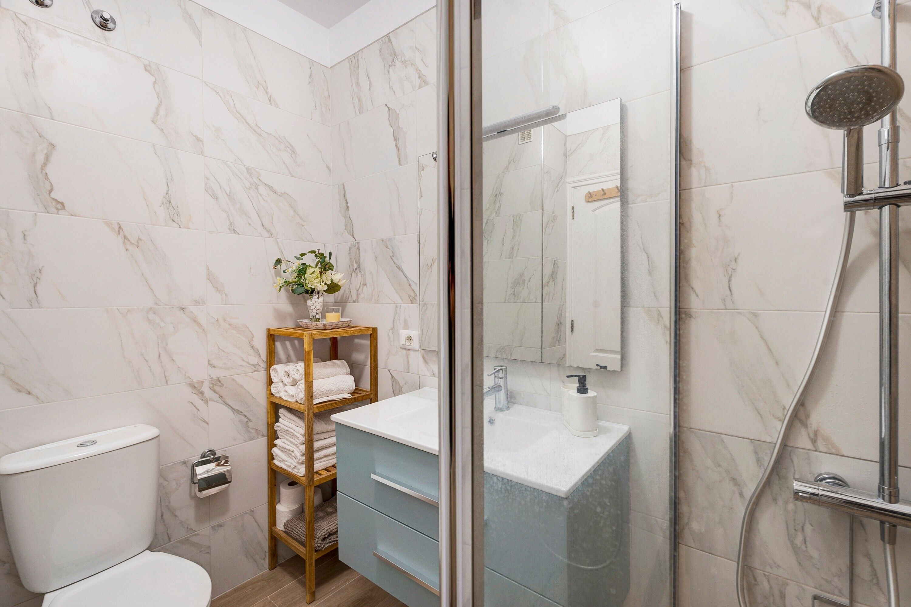A bathroom with a toilet, a sink, a shower, and a glass-enclosed shower area.