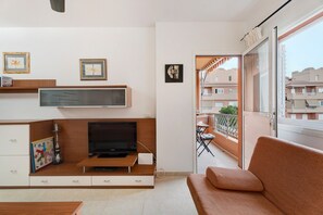Un salon moderne avec un téléviseur, un canapé et des œuvres d’art accrochées aux murs.