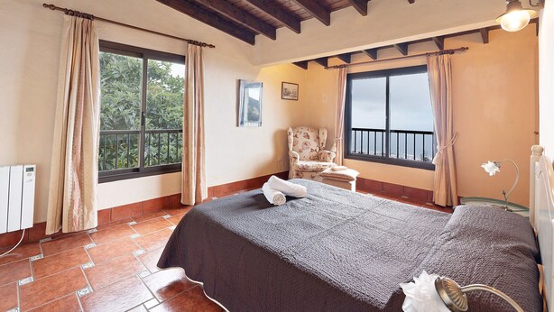 A bedroom with a bed, a chair, a window, and a radiator. - Vacation Home 'Los Nardos' with Sea View, Private Terrace and Private Garden (La Orotava)