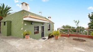 A green building with a tiled roof, a small entrance, and potted plants. - Vacation Home 'Los Nardos' with Sea View, Private Terrace and Private Garden (La Orotava)