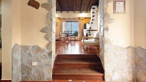 A stone-walled staircase leading to a balcony with a wooden floor, a dining area with chairs, and a kitchen area with a white stove. - Vacation Home 'Los Nardos' with Sea View, Private Terrace and Private Garden (La Orotava)