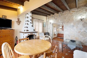 Un intérieur rustique avec un mur en pierre, des meubles en bois, une cheminée et un téléviseur.