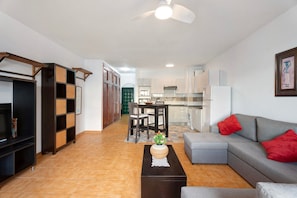 A living room with a sofa, a coffee table, and a TV stand. There is a dining area with a table and chairs. The kitchen is visible in the background. - Holiday Home "Casa Laly" with Sea View, Private Terrace and Wi-Fi (Callao Salvaje)