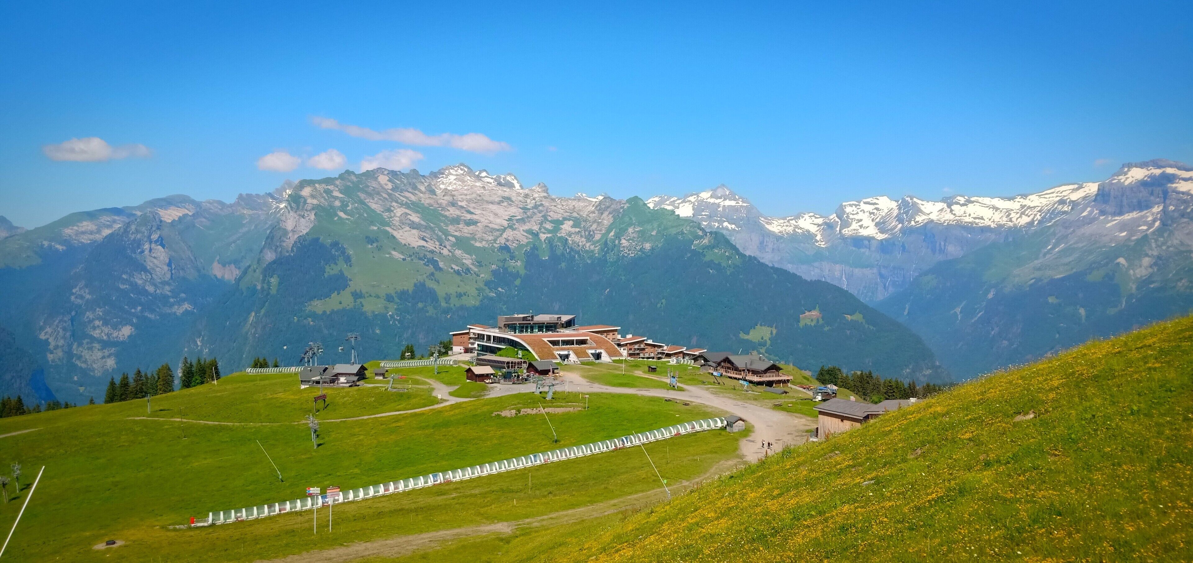 A mountain resort with a central building surrounded by a parking area and a fence.