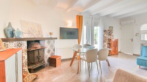 Una sala de estar con chimenea, un comedor con mesa de vidrio y un sofá azul.