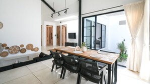 A modern dining area with a wooden table, black chairs, and a ceiling fan.