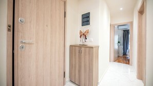 Un pasillo con una puerta de madera, un armario decorado con una mariposa y una vista parcial de un baño al fondo.