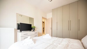 Un dormitorio con cama, televisión, cómoda y armario.