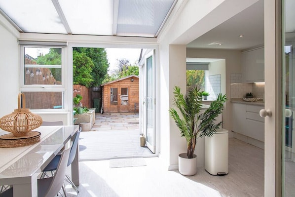 Enjoy a contemporary living space with a dining area, kitchen, and large windows offering a view of the outdoor area.