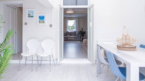 A modern, open-plan living space with a dining area and a sofa in the background. - Stunning Townhouse with Large Garden - Sleeps 8 (Cheltenham)