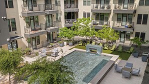Ein mehrstöckiges Wohngebäude mit Balkonen, einem Schwimmbad, Außenmöbeln und Grünflächen.
